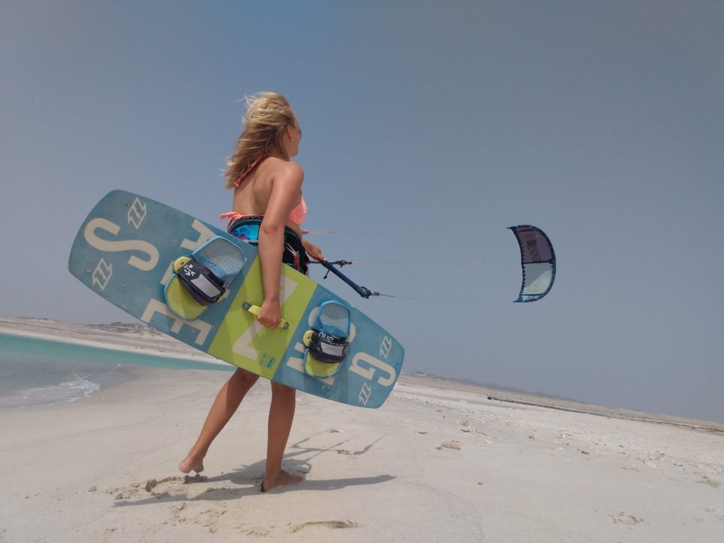 Kiteboarder girl in bikini with kiteboard and kite on a beach in Oman